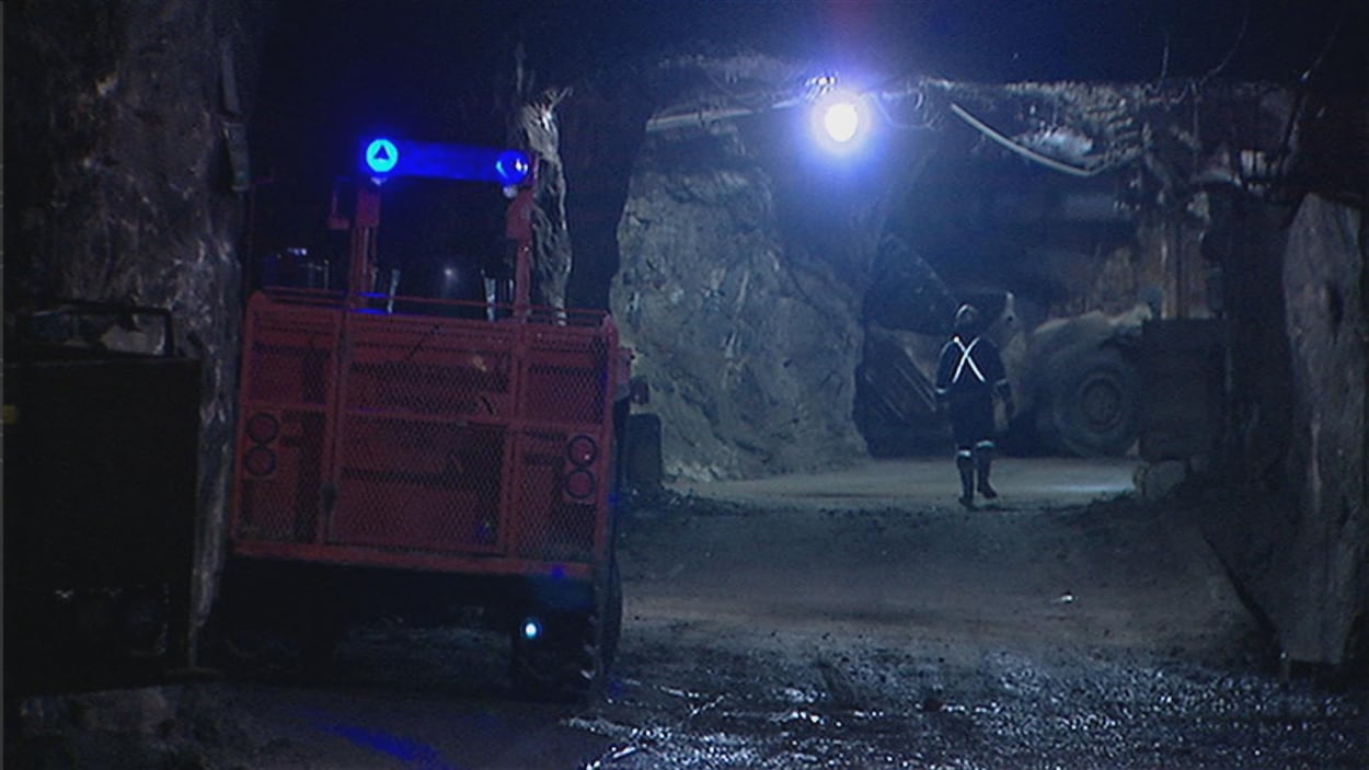 Un travailleur marche dans la mine. Il y a de la machinerie. Un travailleur marche dans la mine. Il y a de la machinerie.