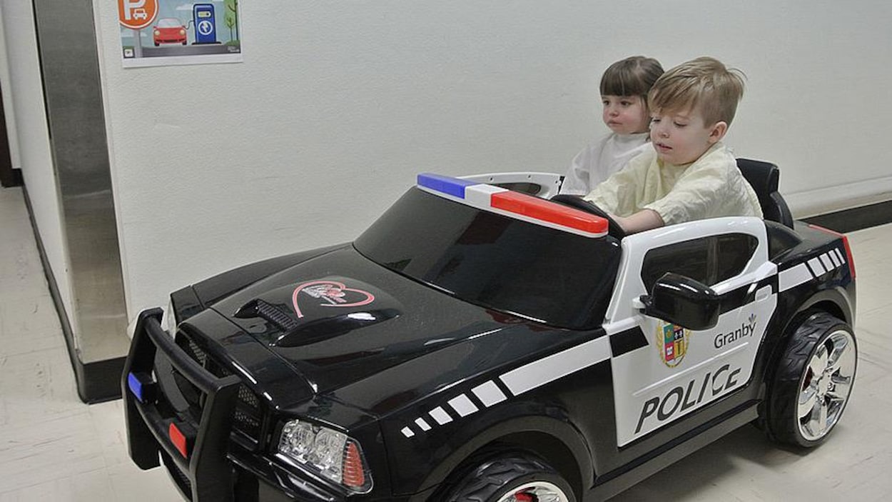 Deux enfants au volant d'une mini voiture aux couleurs du Service de police de Granby.
