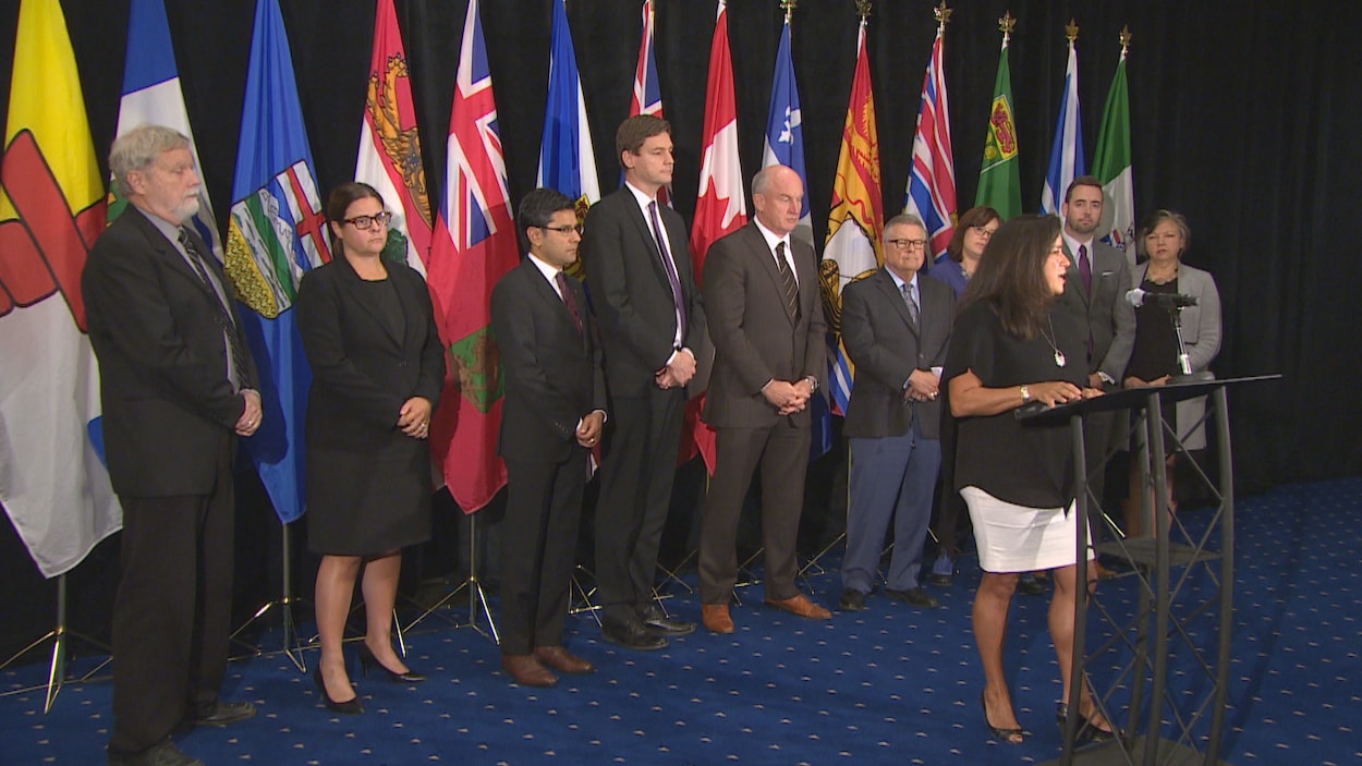 Les ministres en conférence de presse devant les drapeaux du Canada et des provinces. Les ministres en conférence de presse devant les drapeaux du Canada et des provinces.