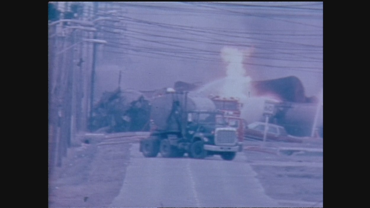 Un train déraillé et du feu, avec un camion de pompier devant.