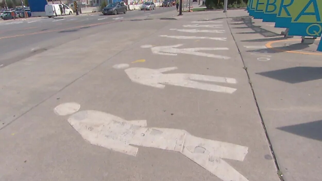 Des piétons sont peints sur une surface asphaltée en bord de route.