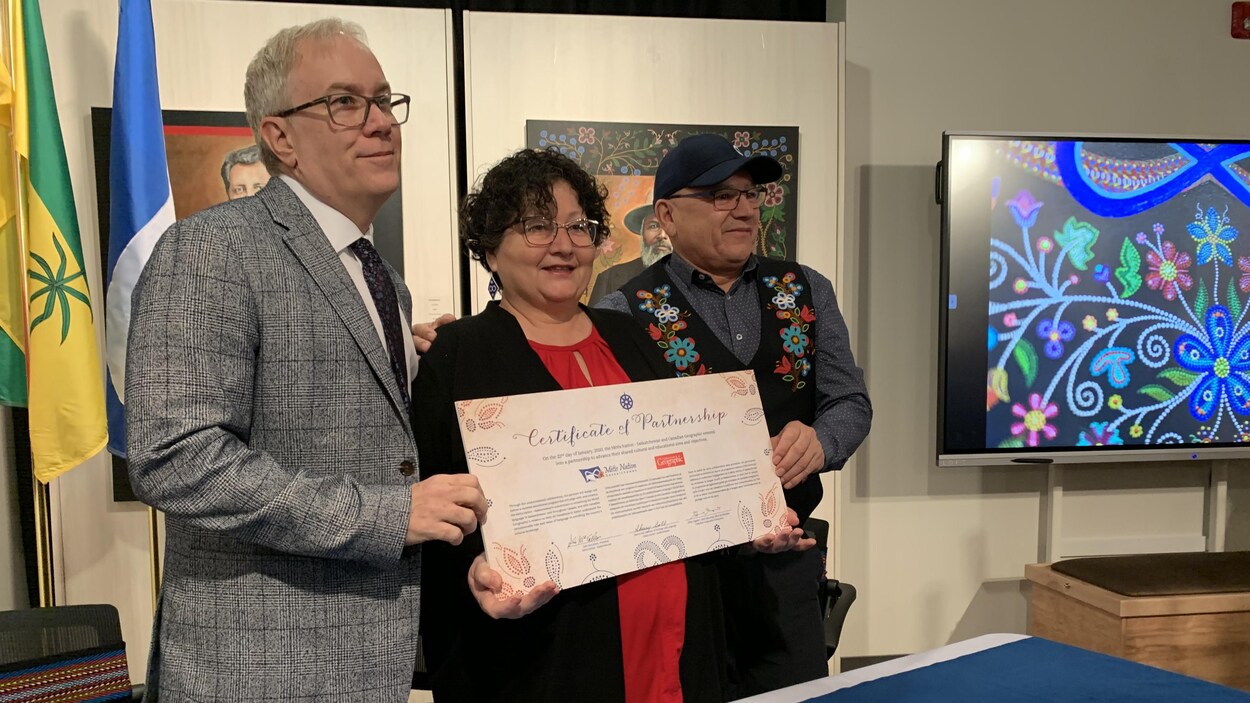 Deux représentants de la Nation métisse de la Saskatchewan et un autre du magazine Canadian Geographic tiennent dans leurs mains un certificat de partenariat.