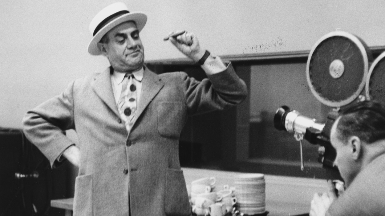 Miville Couture costumé posant devant un caméraman avec un cigare. Miville Couture costumé posant devant un caméraman avec un cigare.