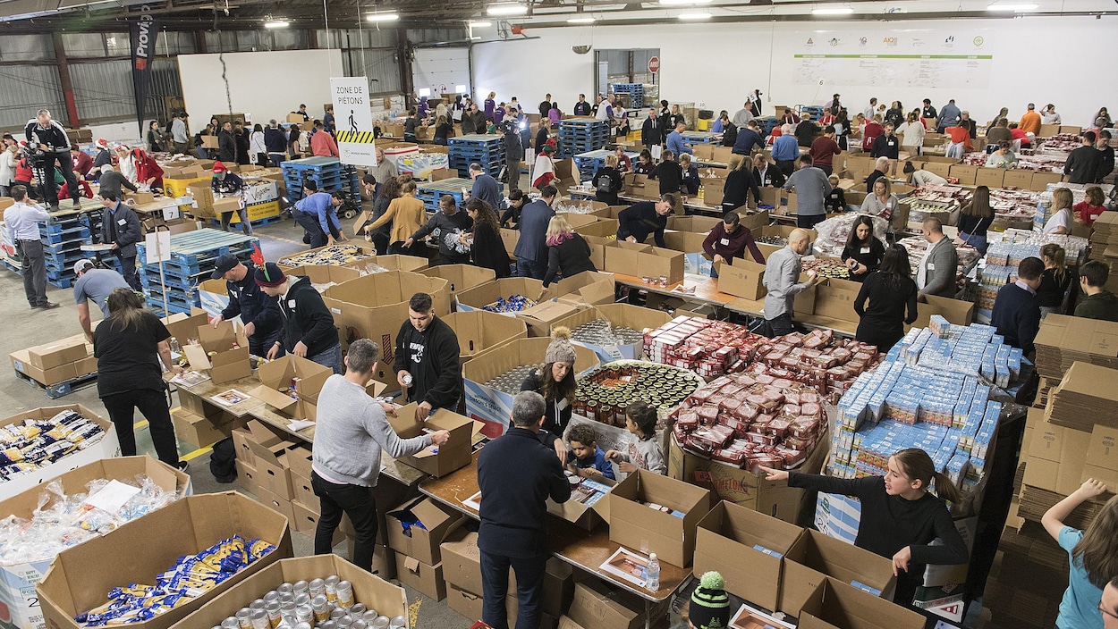 Plusieurs personnes devant d'énormes boîtes remplies de denrées.