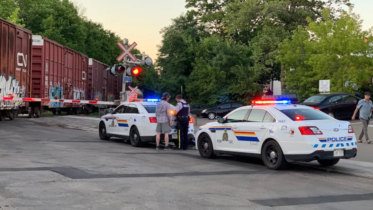 Un policier interroge un témoin devant le train immobilisé