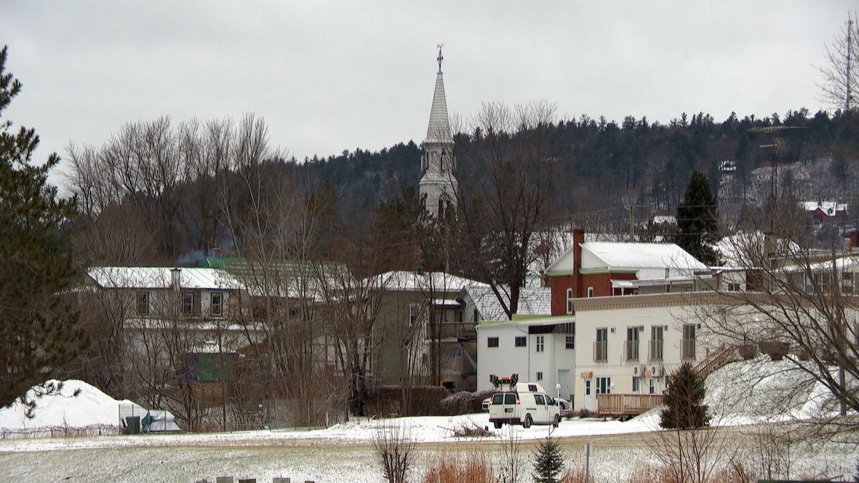 Le village de Montebello en hiver. À travers les maisons, le pignon de l'église est visible.