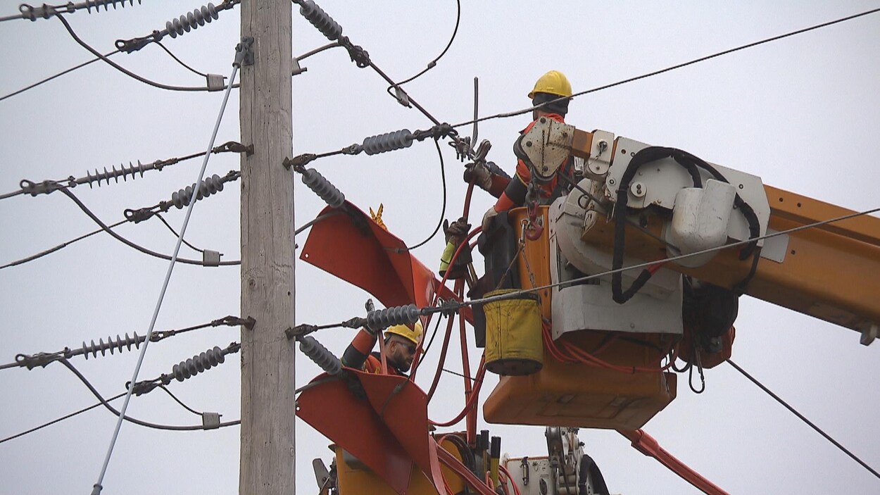 Monteurs de ligne au travail près de fils électriques.