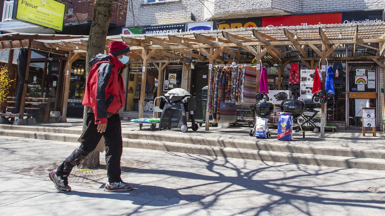 Un homme marche dans rue commerçante. Seul un quincaillier est ouvert.