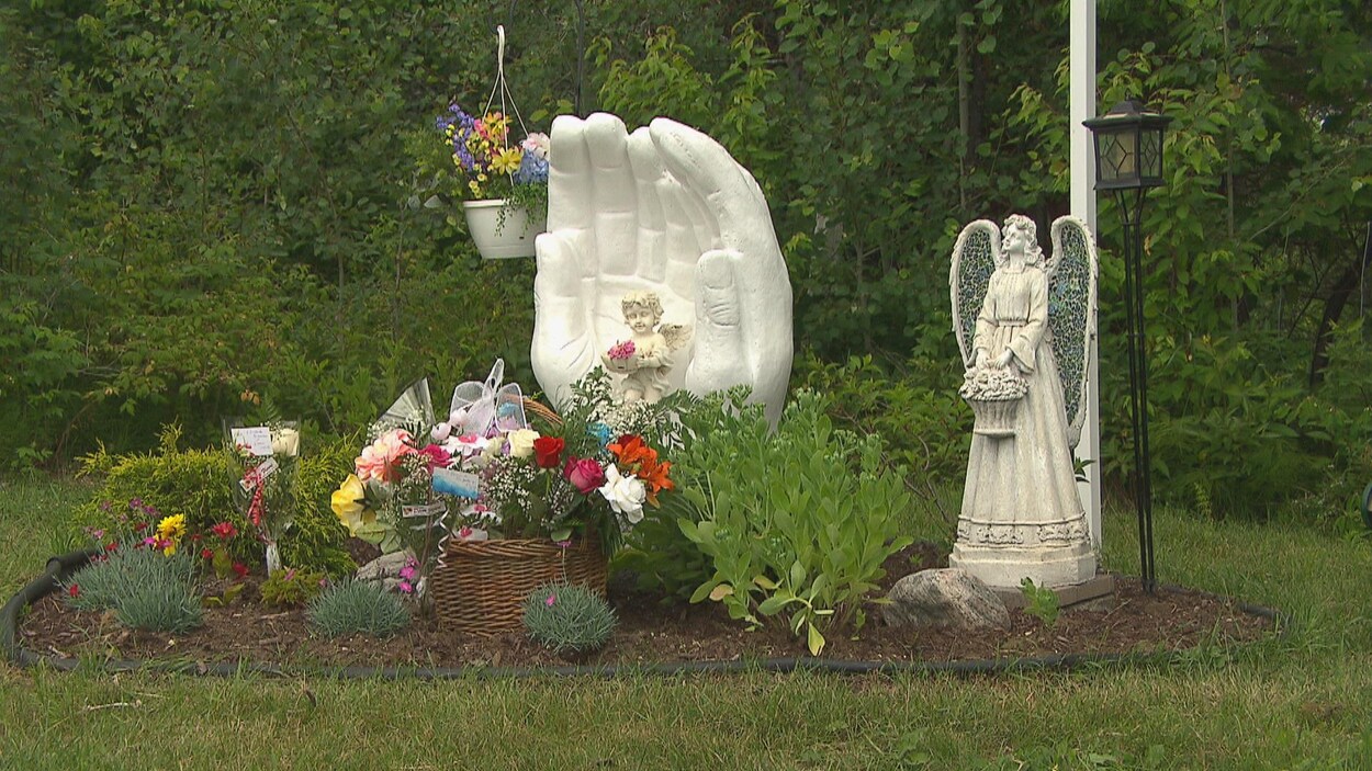 Un monument commémoratif et des statues se trouvent au milieu de fleurs et de plantes.