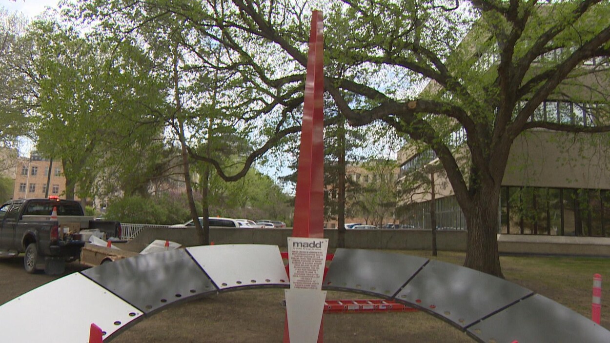 Vue du monument à la mémoire des victimes. Une barre avec à sa base un arc de cercle en métal. Une plaque métallique au milieu porte sur laquelle est inscrit le sigle MADD suivi de la liste de 45 noms de victimes.