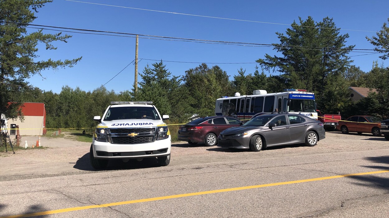 Une ambulance, plusieurs voitures de police et un autobus dans un rang.
