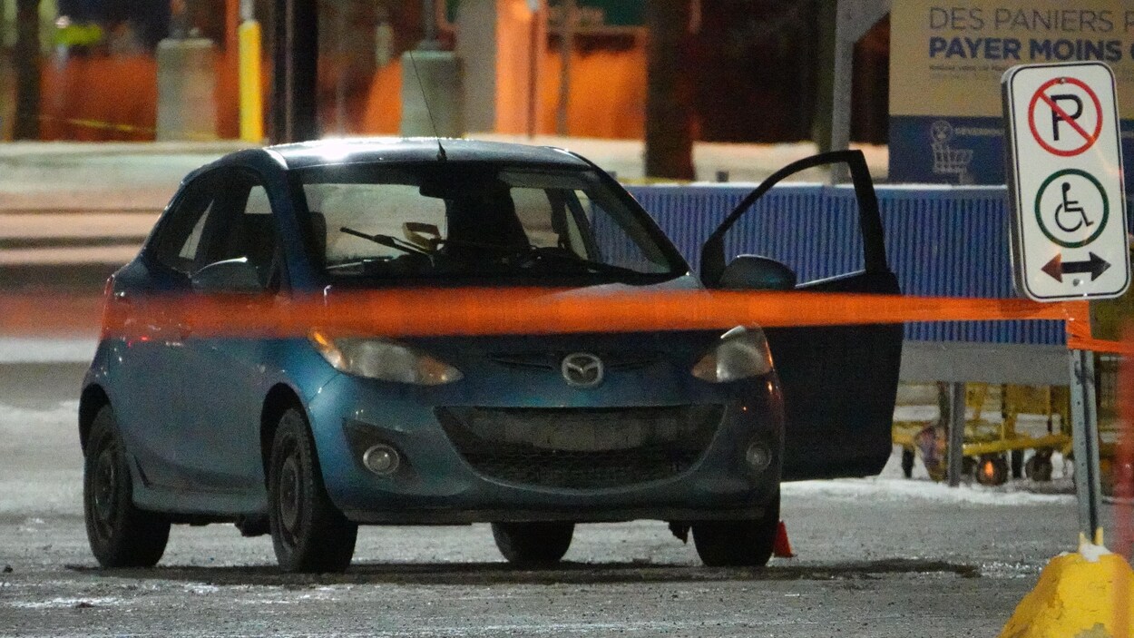 La petite voiture est derrière un ruban de police, une portière ouverte.