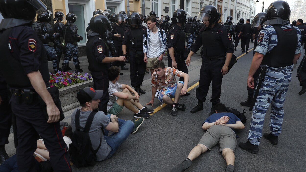 Des manifestants sont allongés par terre, des policiers les encerclent.