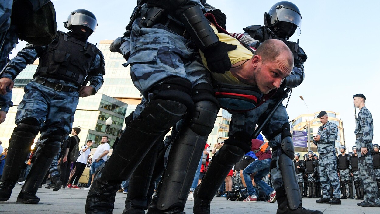 Un homme est retenu par quatre policiers.