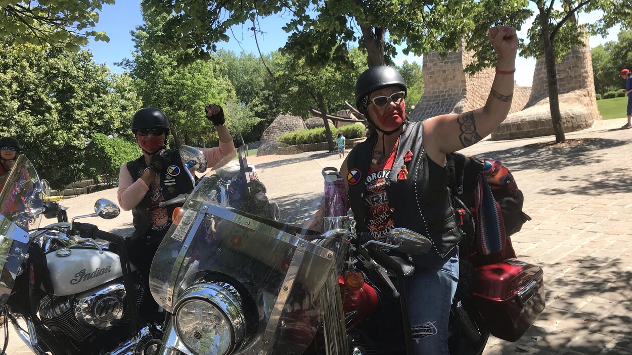 Des motocyclistes avec le visage peint en rouge levant le poing