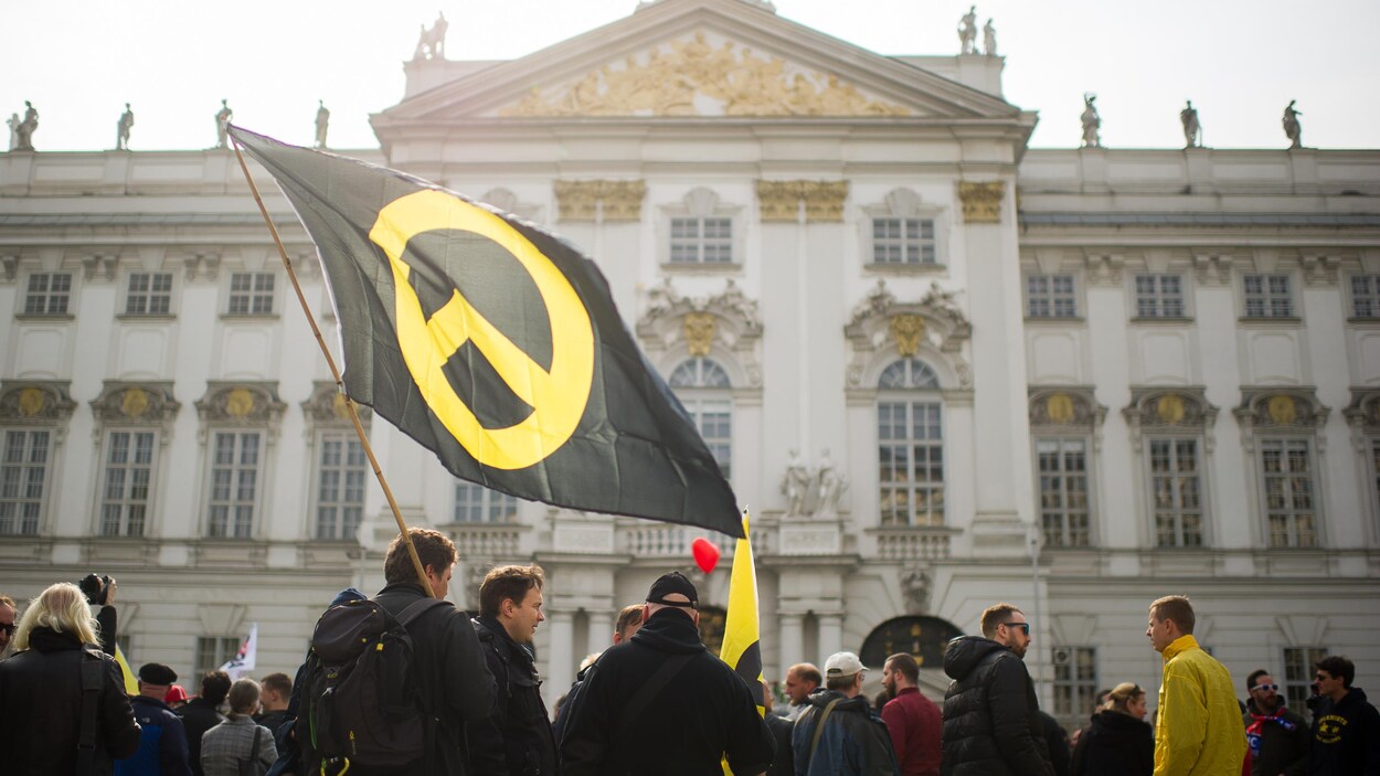 Des manifestants tiennent un gros drapeau avec le logo du Mouvement identitaire, en Autriche.
