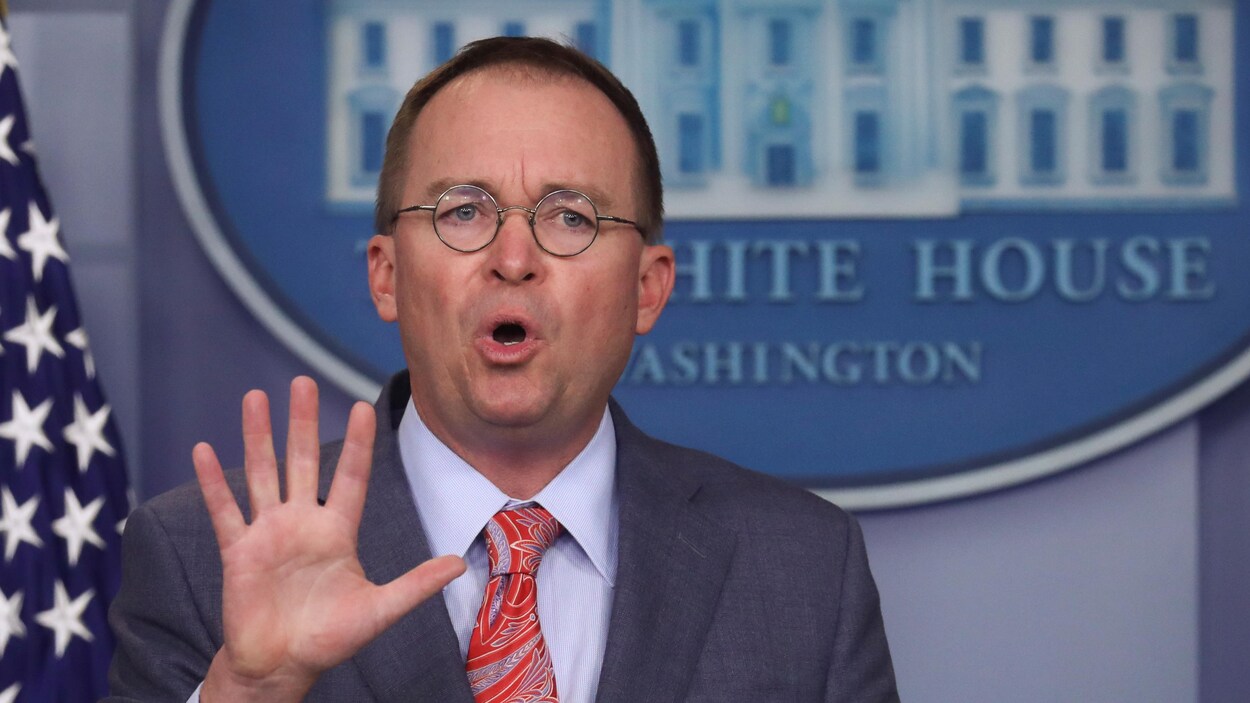 Mick Mulvaney, la main ouverte, répondant aux journalistes.