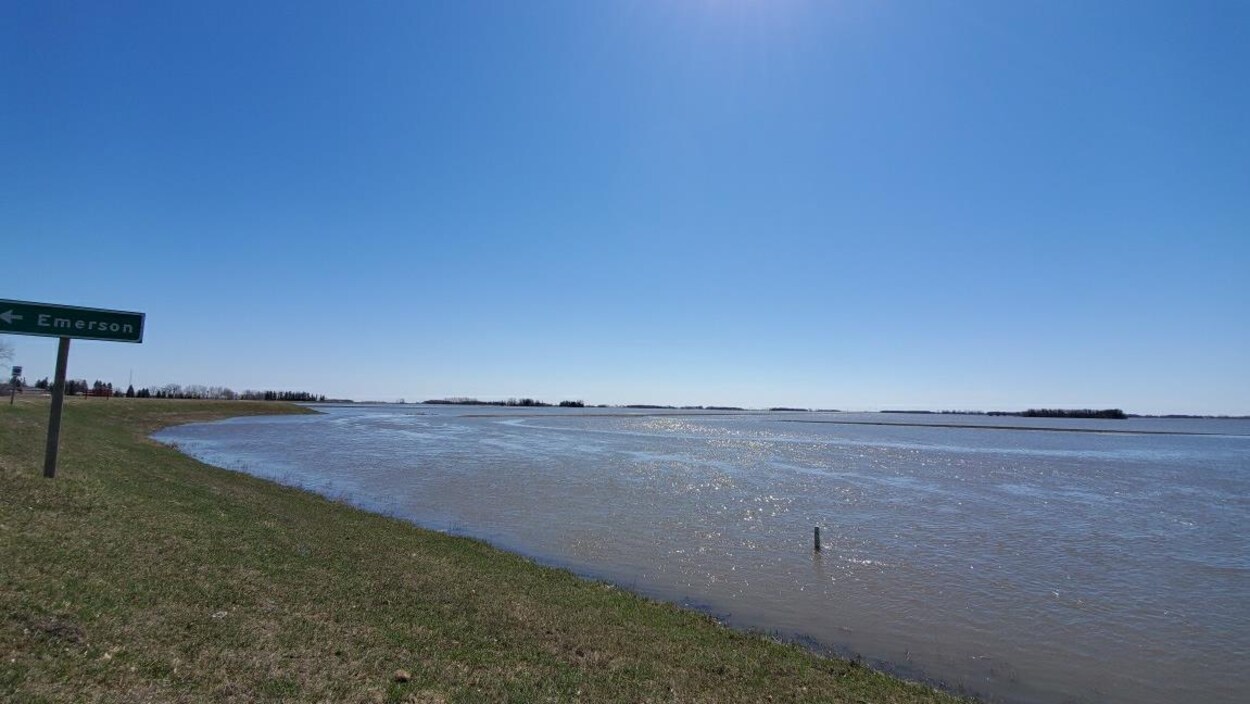 Un champ est inondé et le niveau des eaux se rapproche de la route.