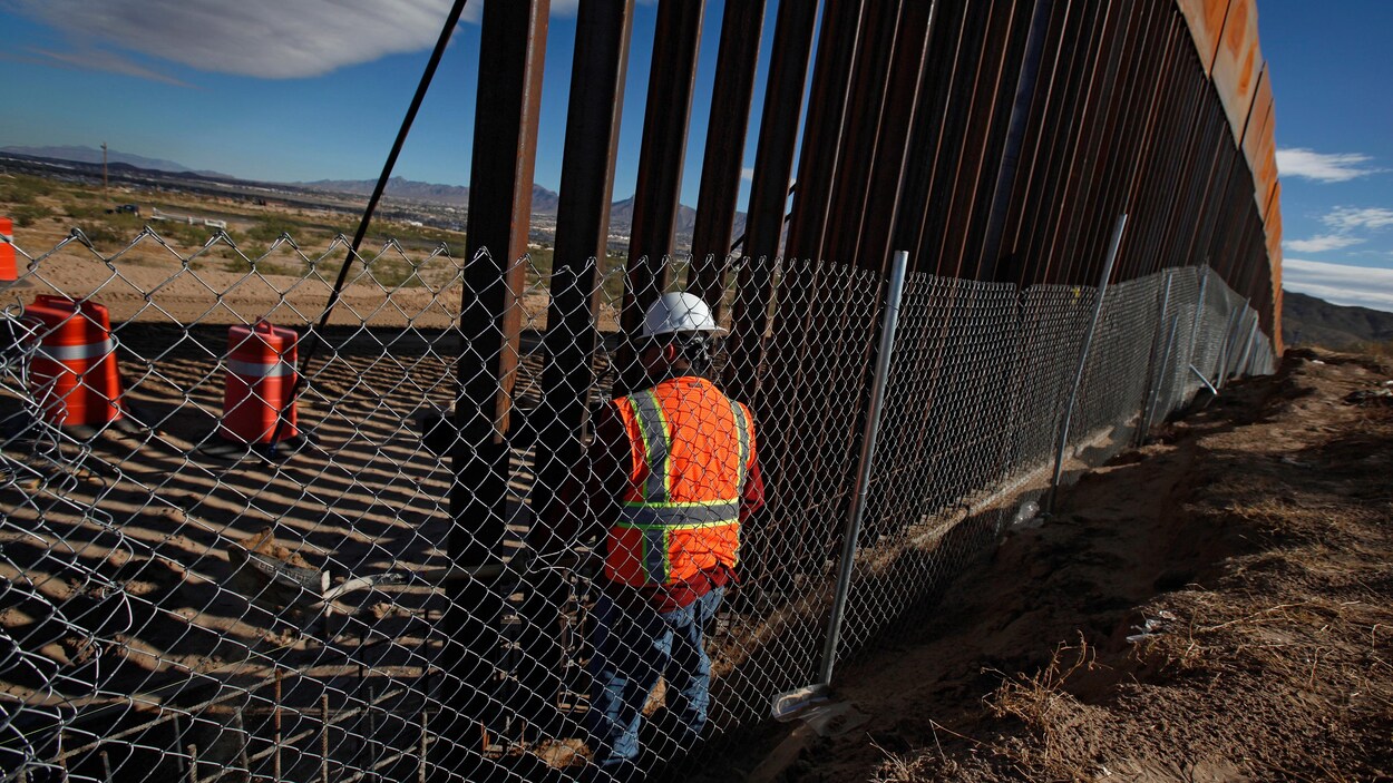 Un homme travaille à la construction d'un mur à la frontière entre les États-Unis et le Mexique.