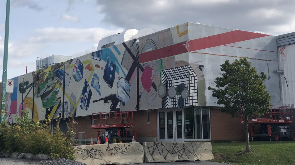 La façade d'un immeuble est peint avec une multitude de couleurs et de formes.