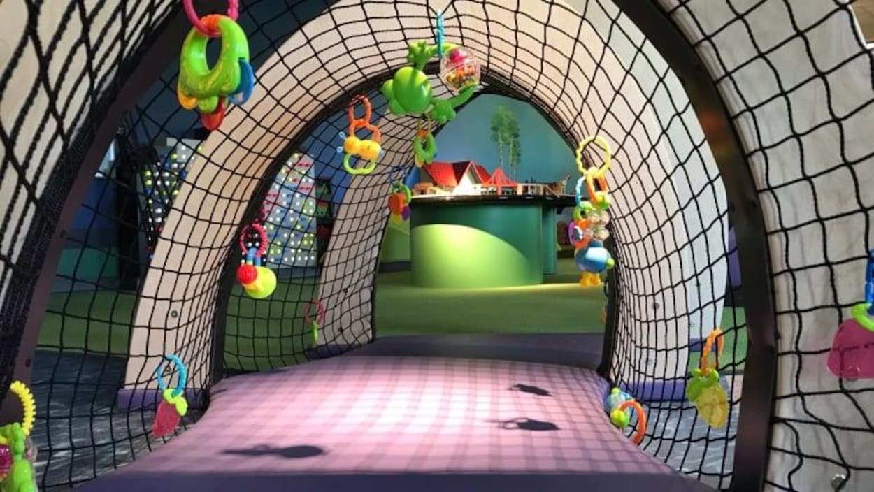 Vue d'un tunnel en filet pour enfants avec des jouets en plastique accrochés ici et là.