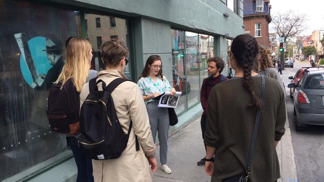 Un groupe de personnes écoute une guide qui fait une visite dans les rues de Montréal.