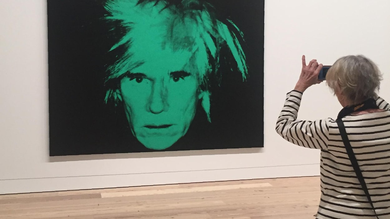 Une femme prend une photo d'une image d'Andy Warhol.