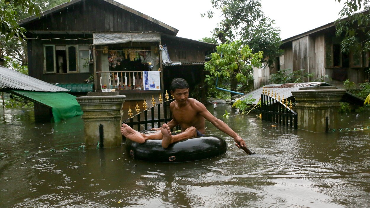 Un homme se déplace sur un tube pneumatique dans une rue complètement inondée.