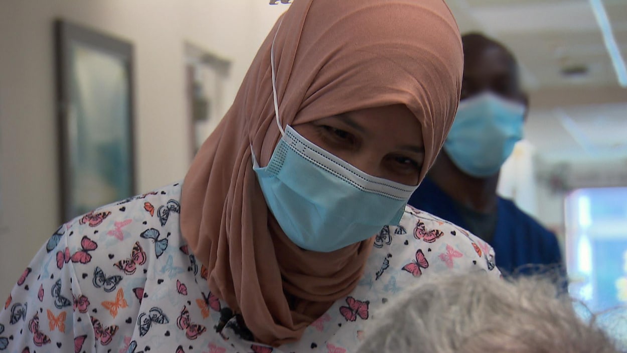 Najwa Essid parle à une patiente dans le couloir d'un établissement de santé.