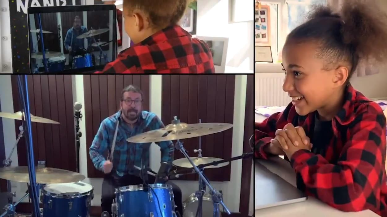 Une jeune fille regarde un écran d'ordinateur sur lequel s'affiche une vidéo de Dave Grohl qui joue à la batterie.