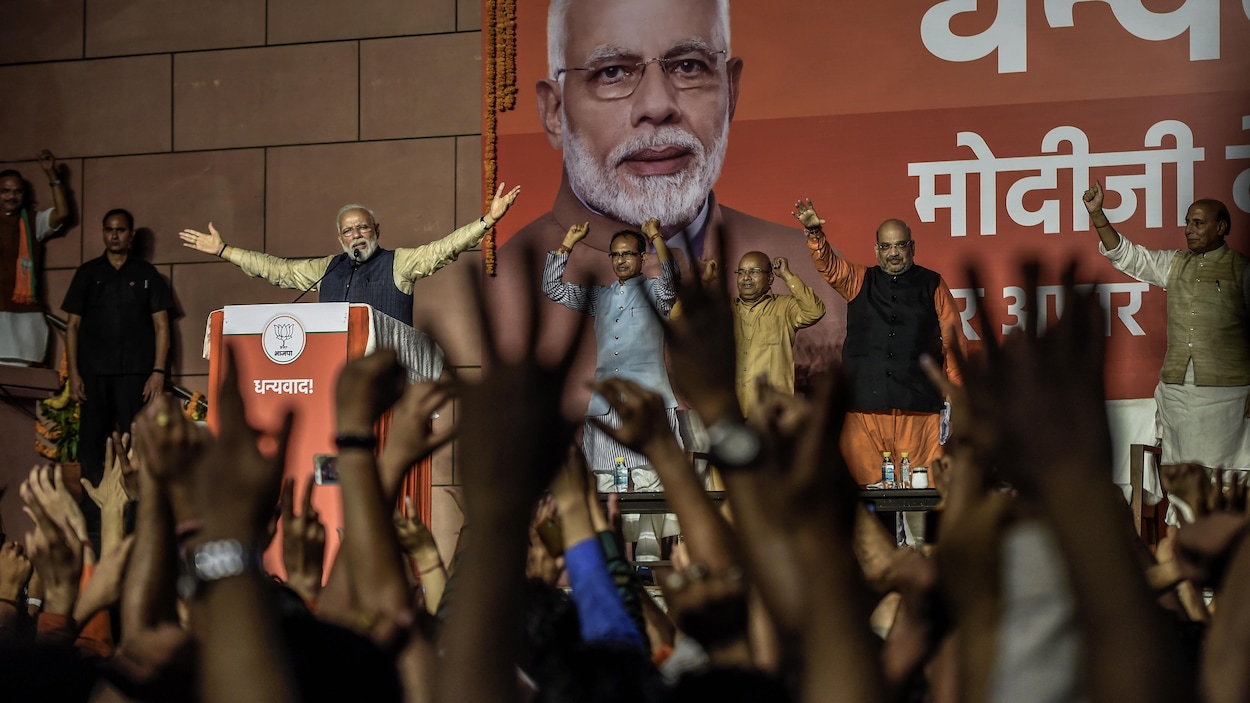 Une foule acclame M. Modi qui lève les bras en signe de victoire.