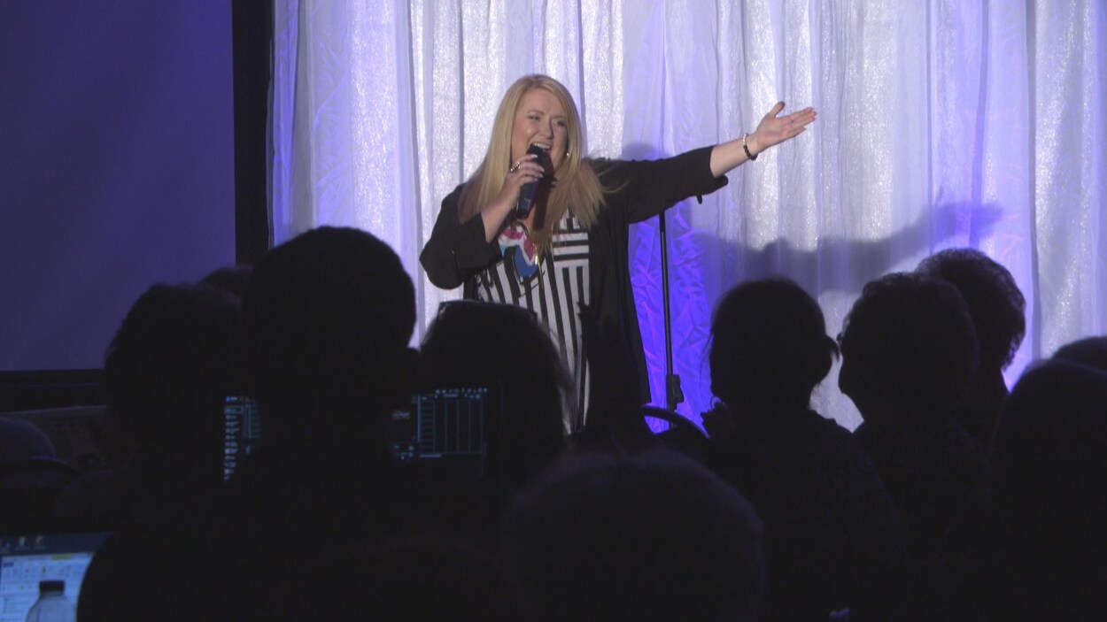 Nathalie Simard chante sur scène devant les spectateurs assistant à sa conférence.