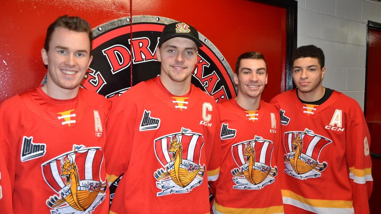 Quatre hockeyeurs du Drakkar sourient à la caméra.