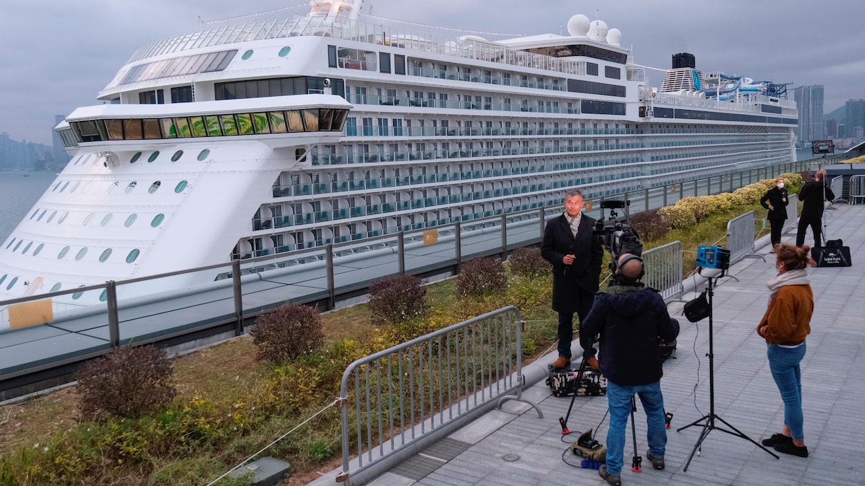 Deux équipes de journalistes de la télévision s'activent, sur la terre ferme, à proximité du navire de croisière World Dream.