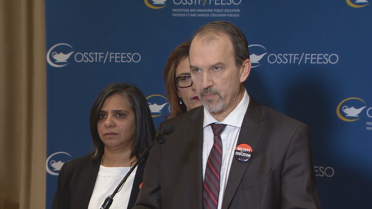 Un homme sur un podium en conférence de presse.