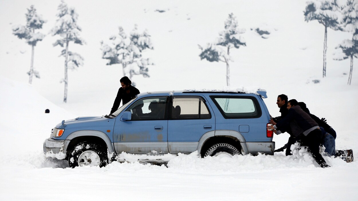 Des hommes poussent une voiture prise dans la neige près de Kaboul.
