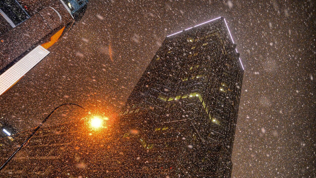 Plan en contre-plongée de la neige qui tombe sur le centre-ville de Montréal.