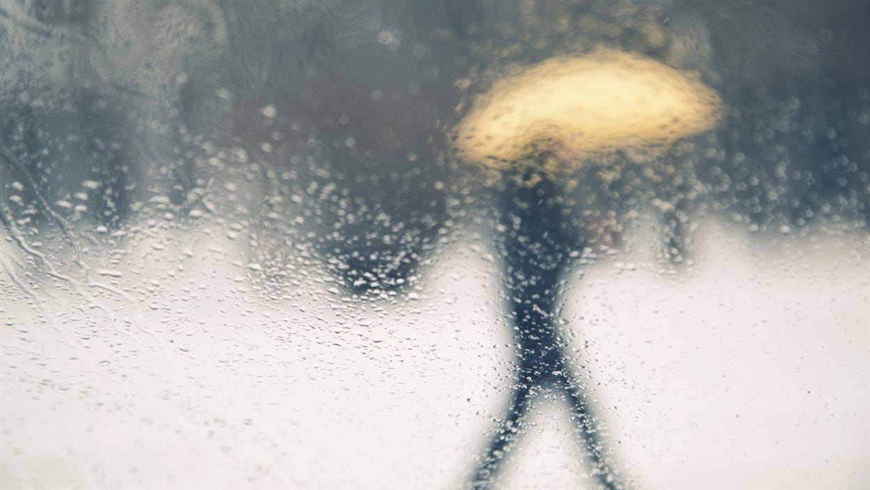 Une personne avec un parapluie marche dans la pluie