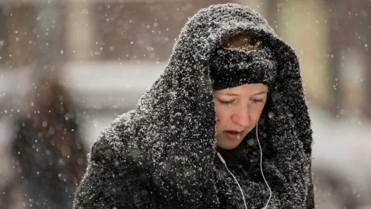 Une femme marche sous la neige.