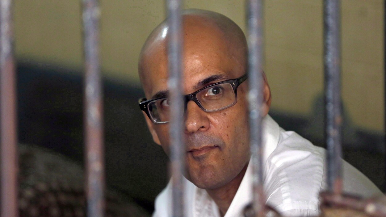 Neil Bantleman vêtu d'une chemise blanche photographié derrière les barreaux.