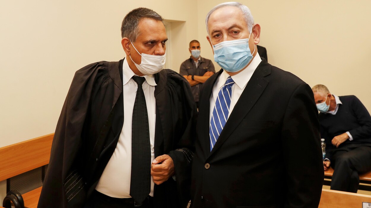 Benyamin Nétanyahou et son avocat, portant des masques chirurgicaux, sont dans la salle d'audience.