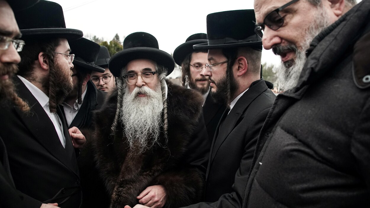 Un rabbin est entouré de plusieurs personnes.