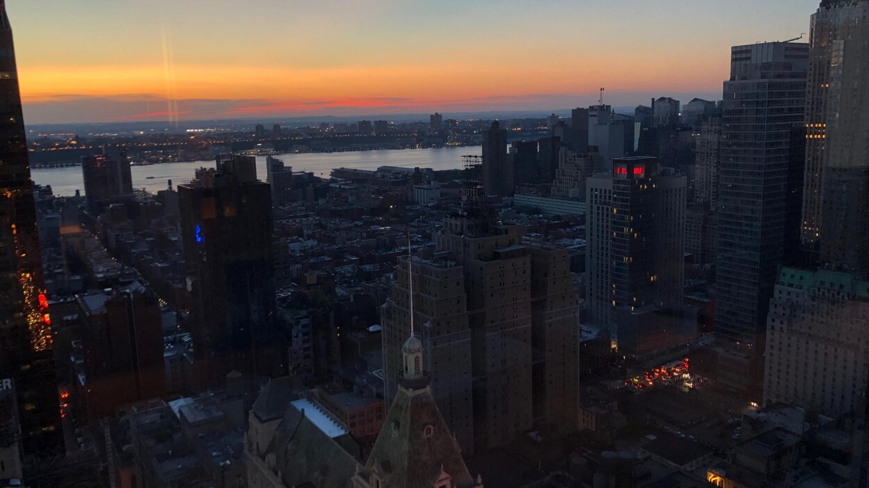 Une vue de la ville à partir d'un gratte-ciel. On voit peu de lumières allumées.