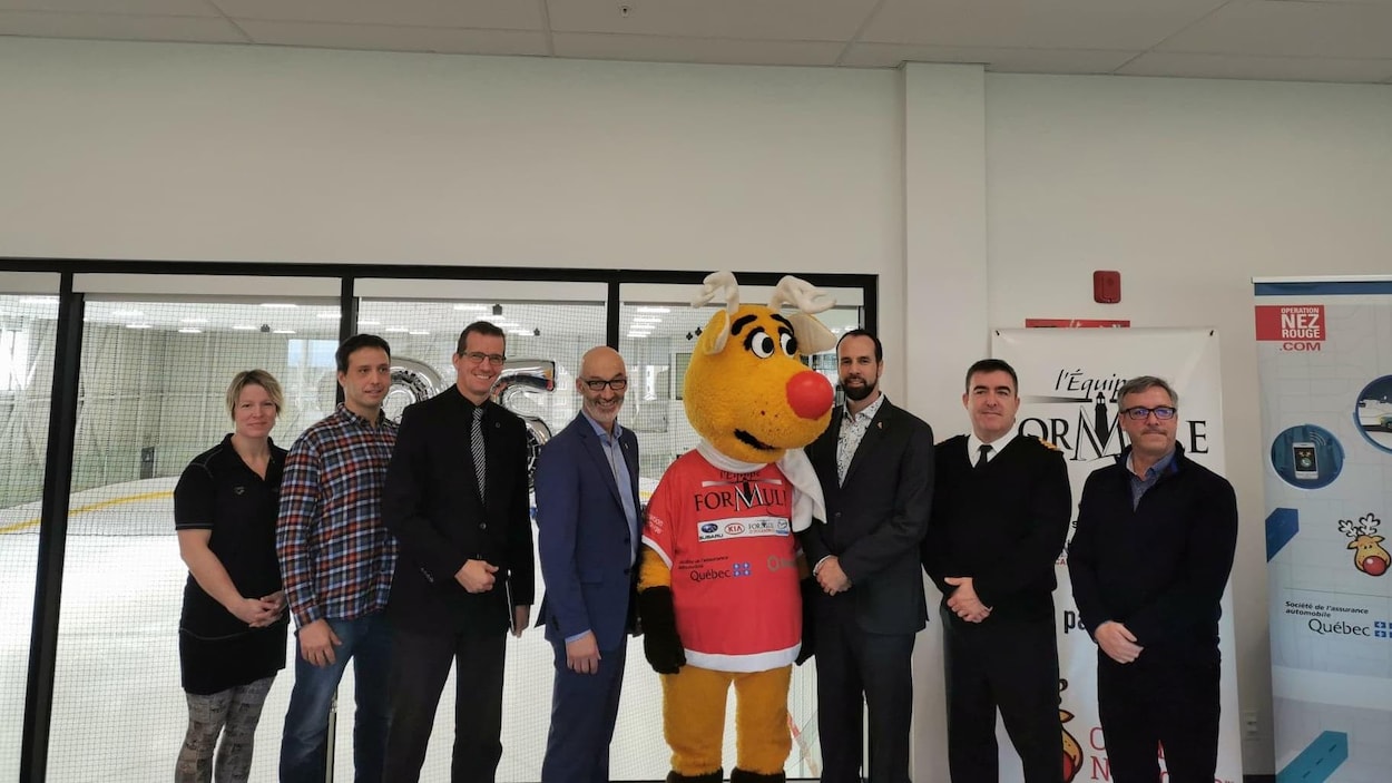 Sept personnes aux côtés de la mascotte de Nez rouge pendant la conférence de presse.