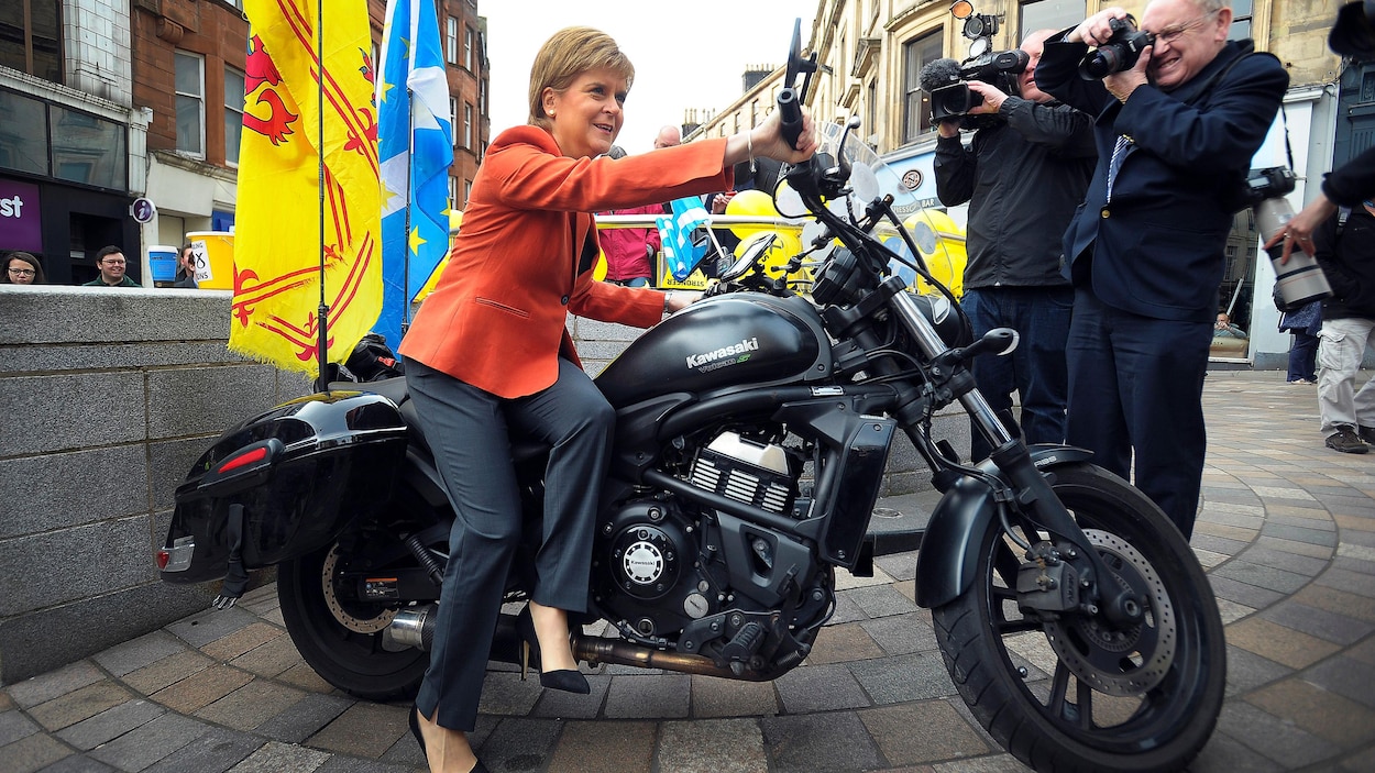 La première ministre écossaise Nicola Sturgeon, sur une motocyclette décorée avec la bannière royale écossaise et le drapeau écossais, est prise en photo. La première ministre écossaise Nicola Sturgeon, sur une motocyclette décorée avec la bannière royale écossaise et le drapeau écossais, est prise en photo.