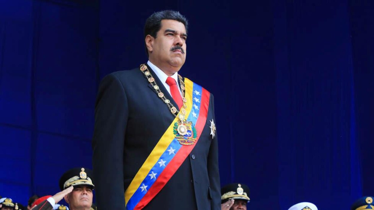 Le président Nicolas Maduro, l'air solennel, se tient sur la scène lors d'un grand événement militaire, à Caracas.
