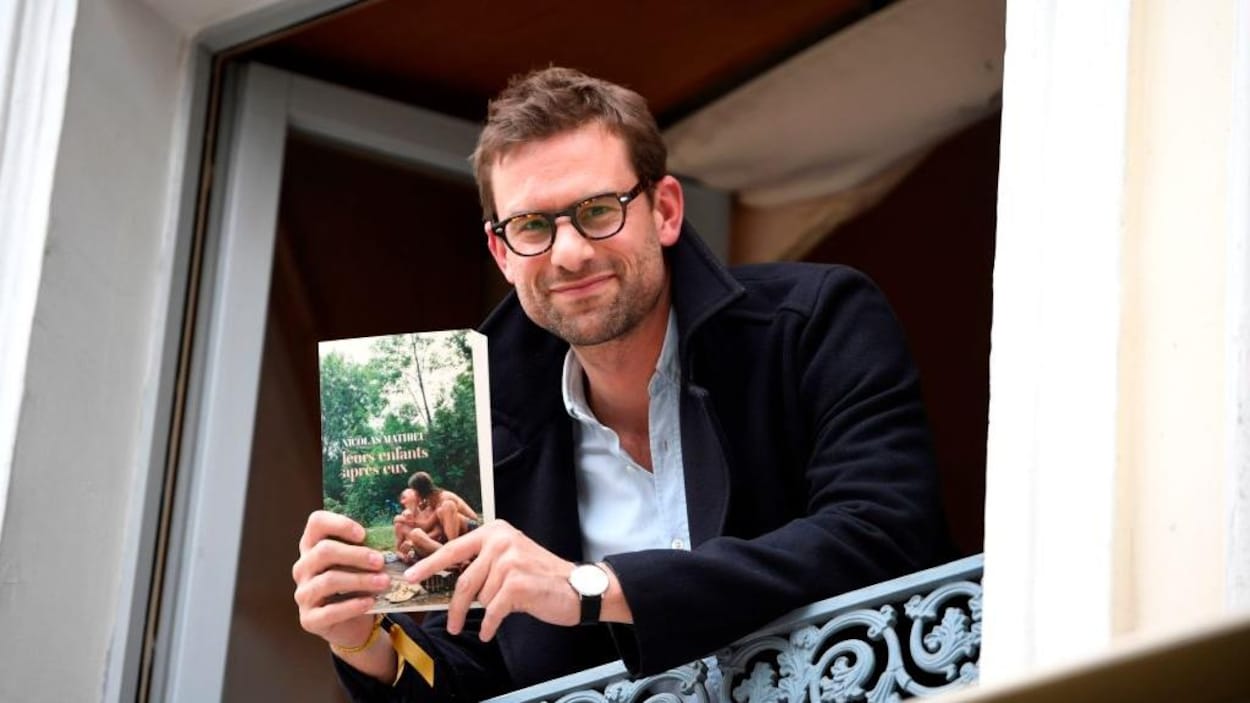 L'écrivain Nicolas Mathieu pose avec son livre à une fenêtre.
