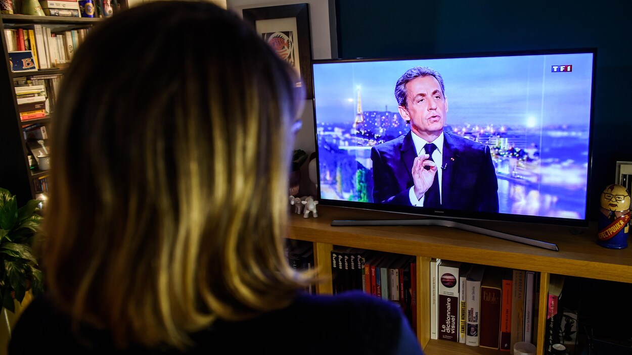 Une femme regarde l'entrevue de l'ex-chef d'État Nicolas Sarkozy à la télé. Une femme regarde l'entrevue de l'ex-chef d'État Nicolas Sarkozy à la télé.