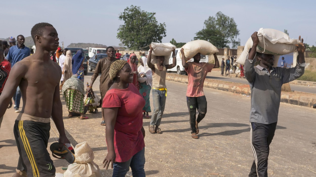 Des gens transportent des sacs de nourriture après avoir pillé des entrepôts où ils étaient stockés.