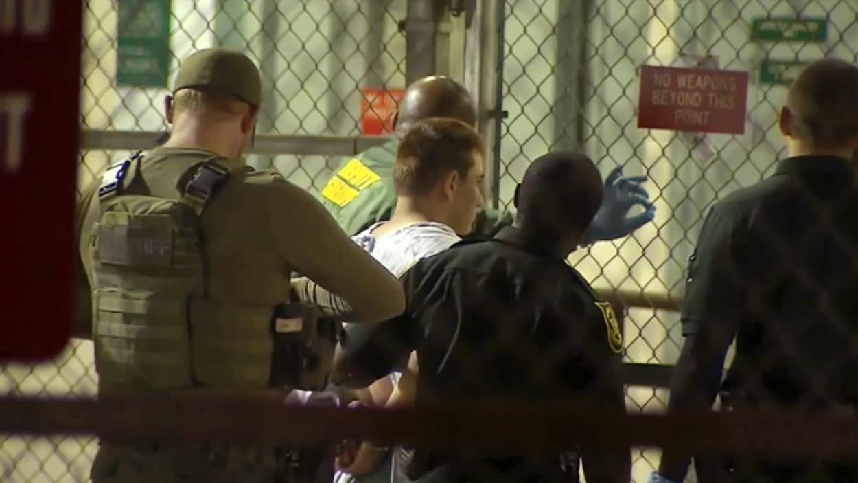 Nikolas Cruz, vu de dos, est escorté par des policiers à son arrivée à la prison du comté de Broward. Nikolas Cruz, vu de dos, est escorté par des policiers à son arrivée à la prison du comté de Broward.